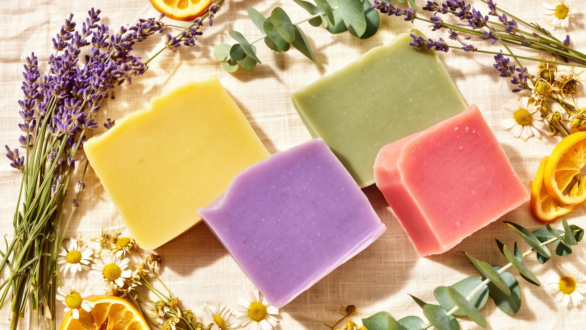 Colourful handmade artisan soap bars surrounded by lavender, eucalyptus and chamomile